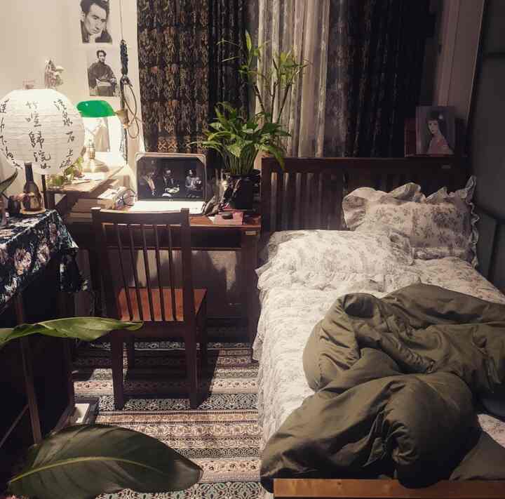 Cozy single bedroom and home office space featuring warm wood tones and green plants