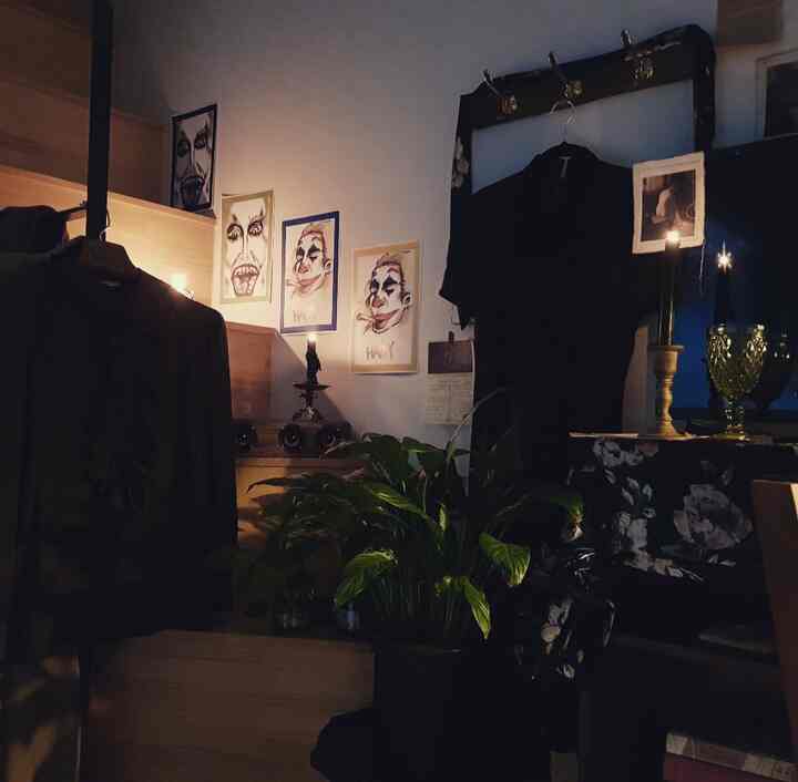 Cozy bedroom with dim lighting, vintage furniture, Joker artworks, and candle holders creating moody atmosphere