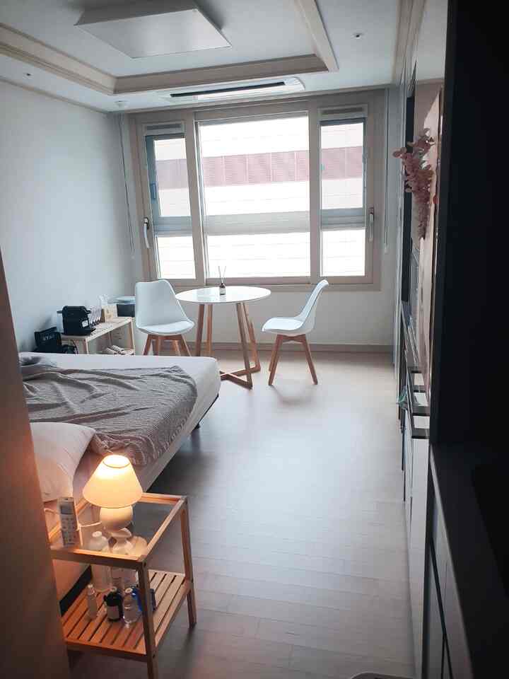 Bright white and natural wood tone 6-pyeong studio apartment featuring a round table and bed in a neat layout