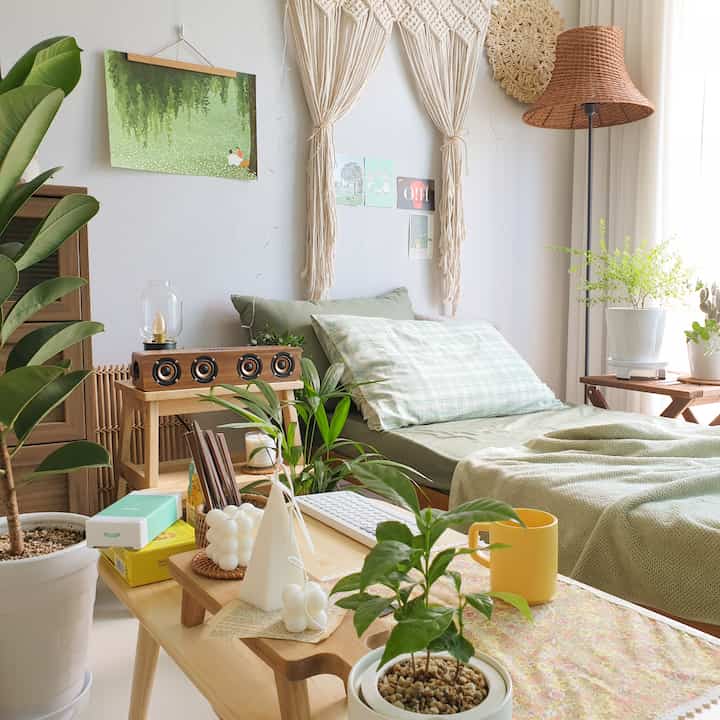 Natural-toned bedroom featuring green bedding and various plants creating a cozy space