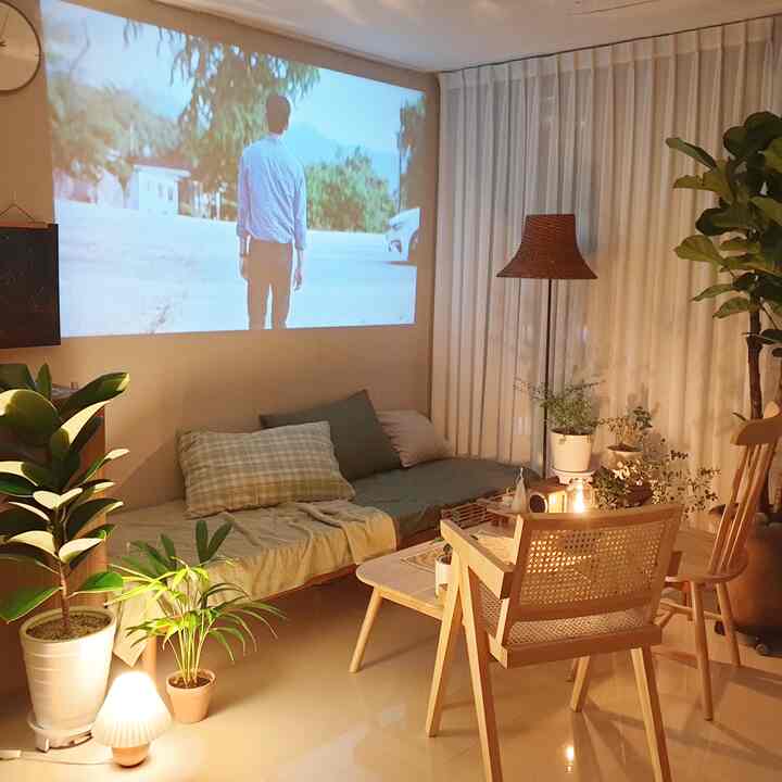 白と木目調が調和したワンルーム寝室、プロジェクターとラタンランプが印象的なホームシネマ空間を演出