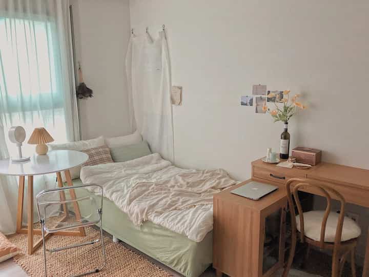 Ivory and wood-tone studio bedroom featuring simple furniture and natural decor creating a calm space