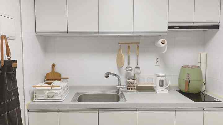 白とナチュラルウッド調が調和した清潔感あるキッチン、シンクと調理器具が整った実用的な空間