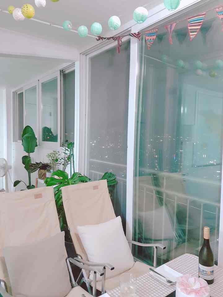 White-walled veranda featuring light beige relax chairs, plants, garlands, and a cozy home camping atmosphere