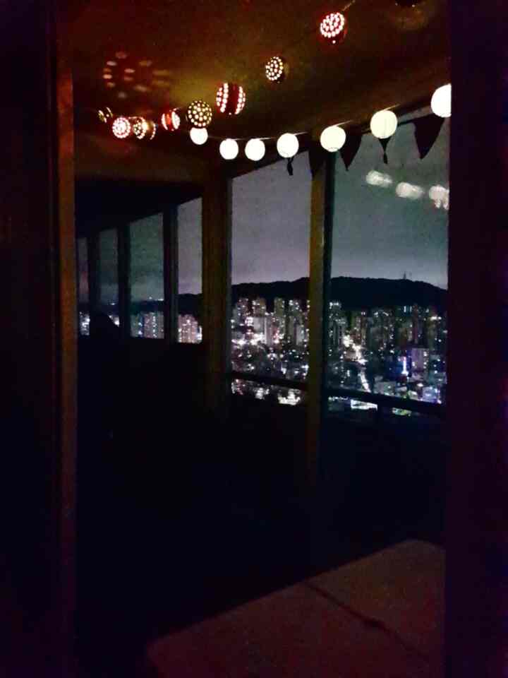 ベージュとブラックの色調の夜景が見えるベランダ、LEDストリングライトが温かみのある雰囲気を醸し出す空間