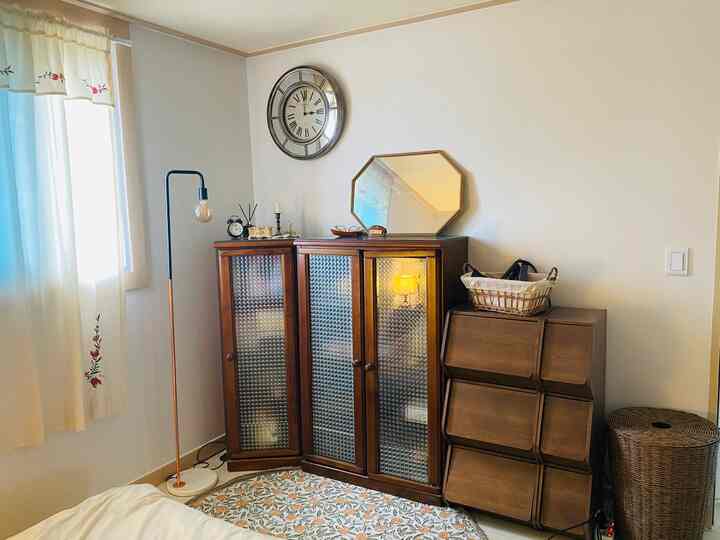 Beige and brown toned bedroom corner featuring wooden storage cabinets and a floor lamp in a natural modern style