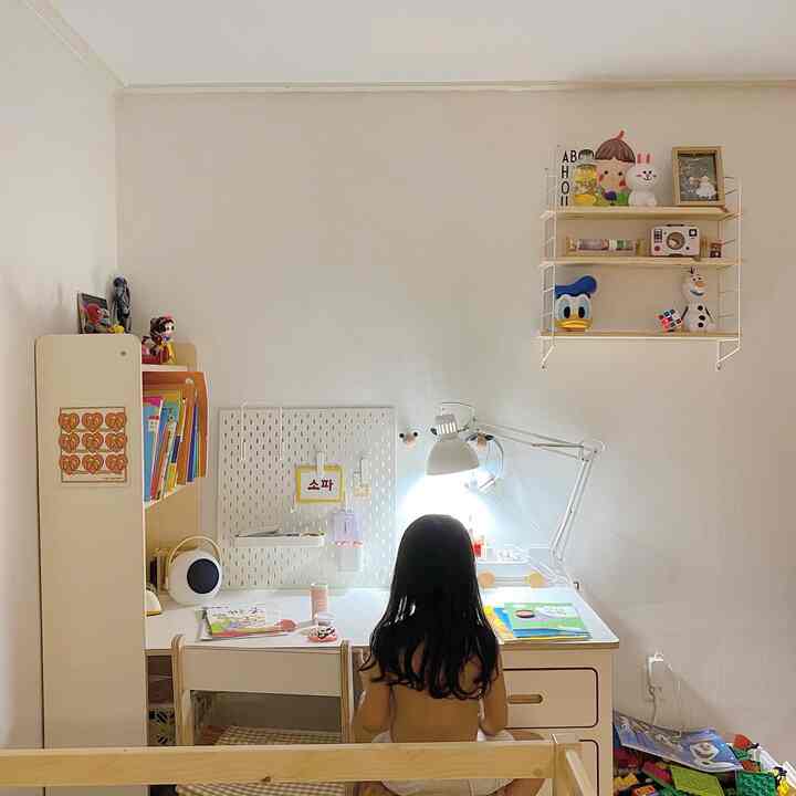 ナチュラルカラーの子供部屋、木製の机と壁棚が配置され、雰囲気のある勉強空間