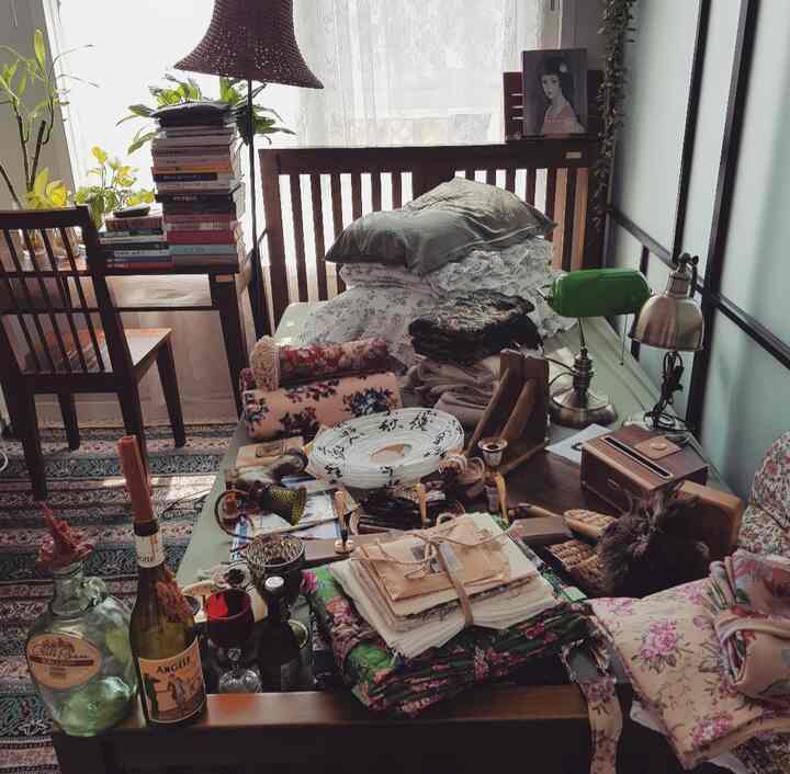 薄いミント色の壁と木製家具、ヴィンテージ小物が散らかったワンルーム寝室の雰囲気あるインテリア