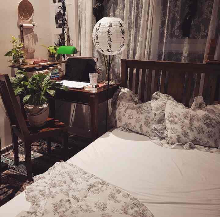 Cozy bedroom with natural wood tones and white hues, featuring a desk and plants creating a relaxing atmosphere