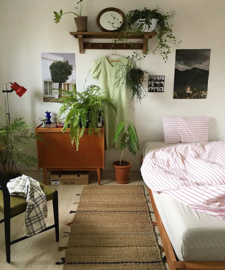 ナチュラルな色調の寝室で、木製家具と多くの植物が配置された雰囲気のあるインテリア。