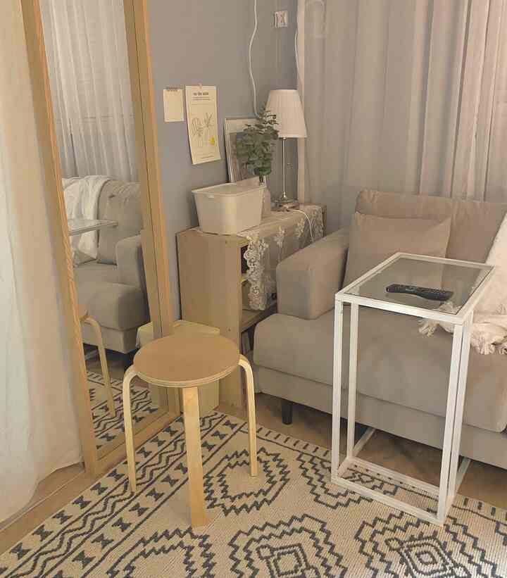 Beige and white toned studio living room featuring cushioned sofa and patterned carpet in natural modern style