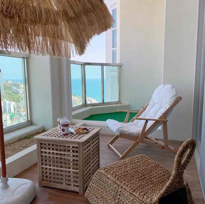 Wood tones and white colored veranda featuring a folding armchair and wooden side table creating a cozy relaxation space with sea view