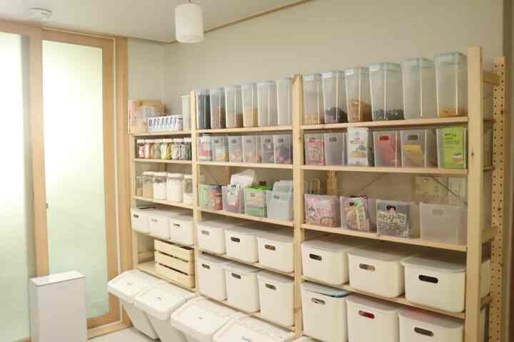 ホワイトとナチュラルウッドトーンが調和したパントリー、透明およびホワイトの収納容器が整然と配置された印象的な空間