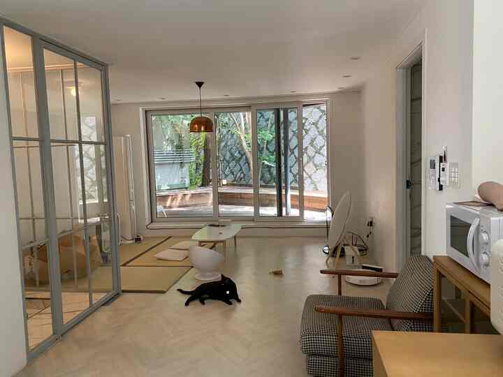 Natural tone living room with tatami flooring, featuring a low table and a black cat for a peaceful atmosphere