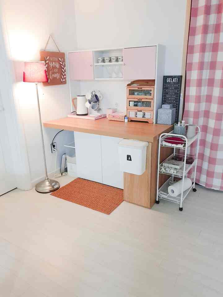 White and natural wood tone kitchen space with pink accents, featuring a clean modern style and organized storage and beverage area