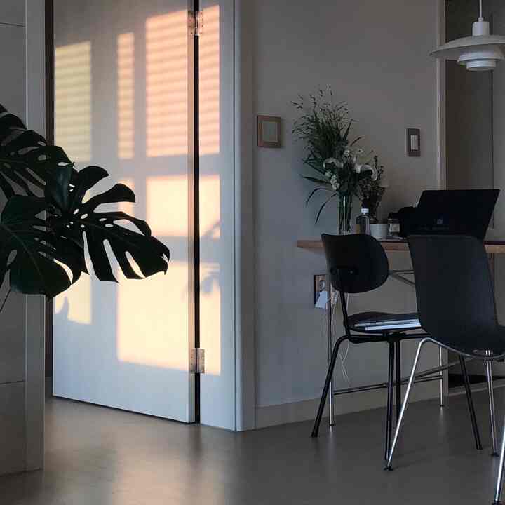 柔らかなナチュラルトーンのキッチン空間、ダイニングテーブルに花瓶とノートパソコンが配置され、温かみのある在宅勤務の雰囲気を演出