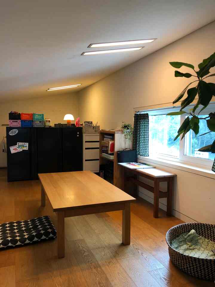 ナチュラルな木目調と低い天井が印象的なロフト、中央に座卓と整頓されたイケアのキャビネットが配置された温かみのあるインテリア