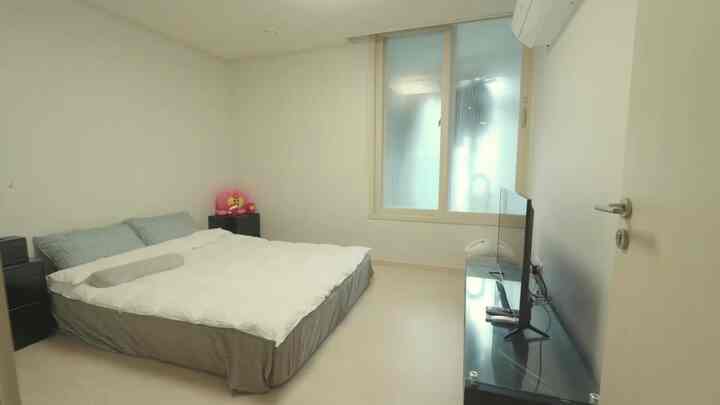 A white and black monotone bedroom featuring a low bed centered with black nightstands on each side, simple and minimalistic space