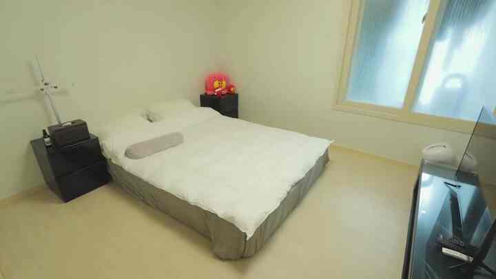 ホワイトとブラックの調和が取れたモダンな一人暮らし用寝室、中央に大きなベッドと両側にナイトテーブルが配置された整った空間