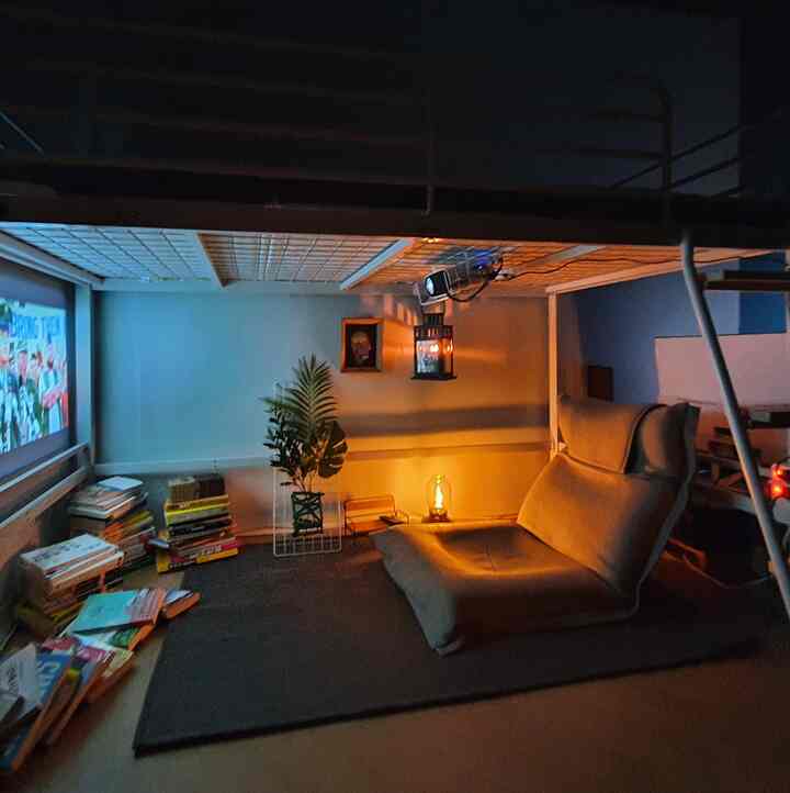 Cozy bedroom home cinema space with warm lighting featuring a natural-tone bunk bed and piles of books