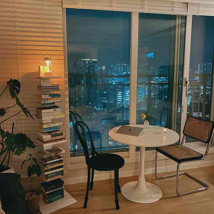 White and brown toned living room featuring a bookshelf and round dining chairs creating a cozy home cafe atmosphere