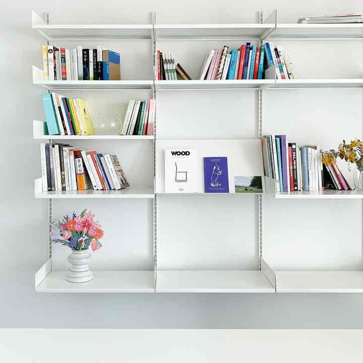 White-toned study space featuring a centrally mounted bookshelf on the wall and a simple desk with a clean interior