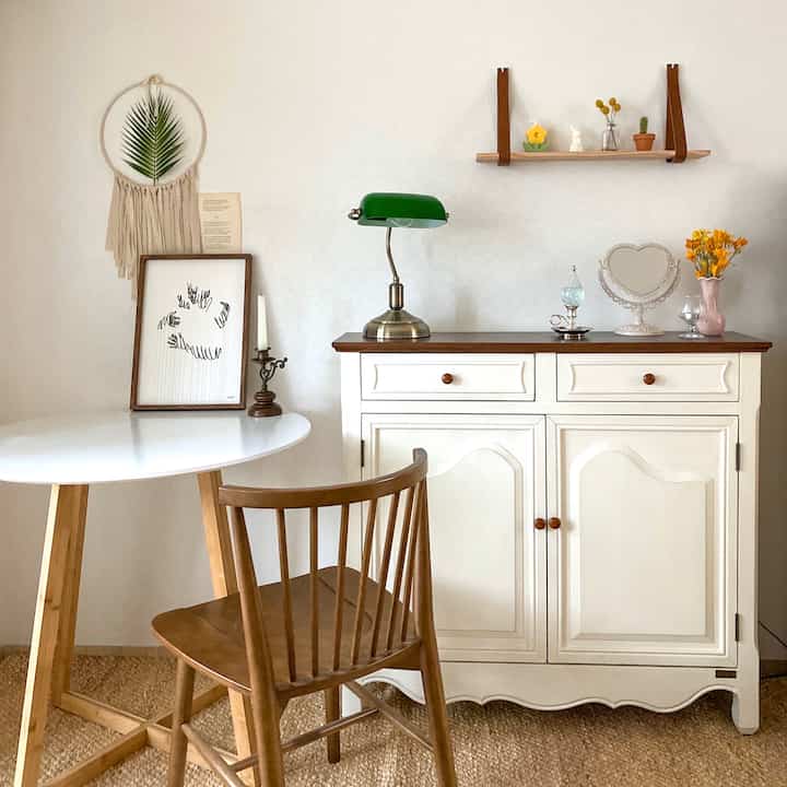 Natural cafe-style space with white walls and brown wooden furniture, featuring a console table and round table in a cozy home cafe