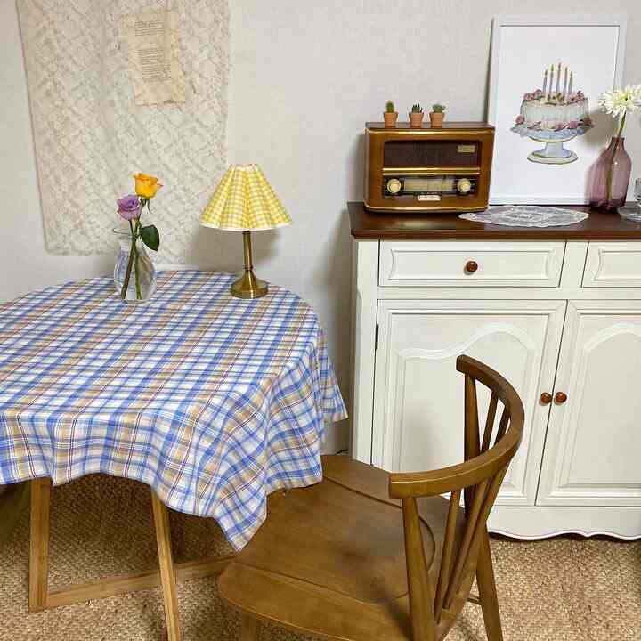Natural toned small home cafe space featuring a round dining table, vintage radio, and vase with flowers creating a cozy ambiance