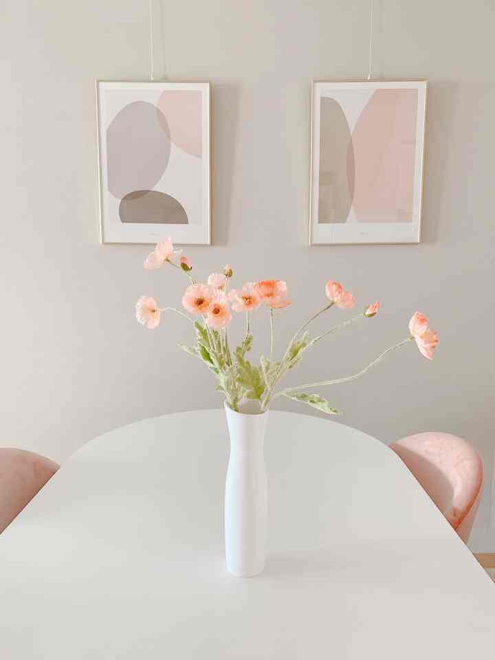 Ivory and pink toned dining room with a central vase featuring poppy artificial flowers as a focal point