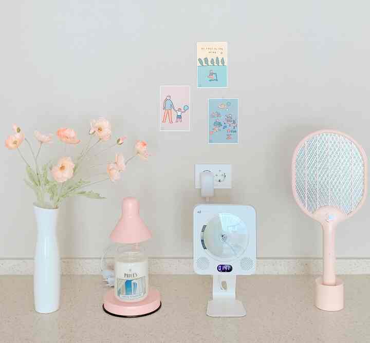 ベージュトーンのキッチン空間、ピンクの造花、キャンドルウォーマー、電気蚊取りラケットが整然と配置された落ち着いたインテリア