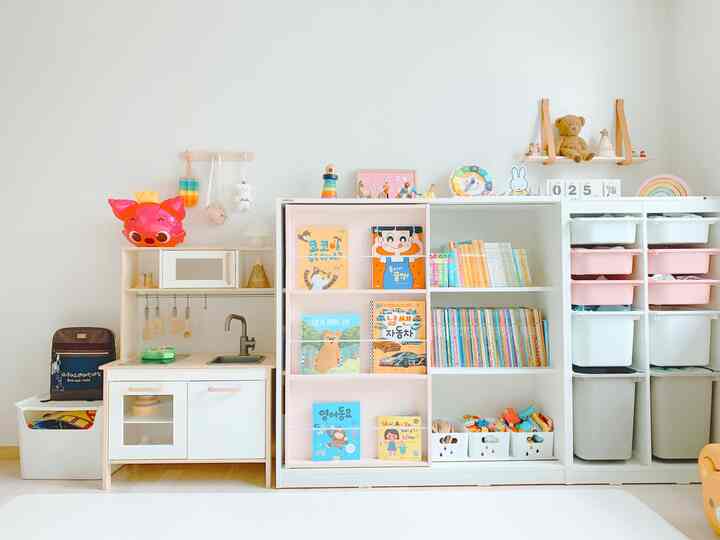 明るい白と木目調の子供部屋、スライディング本棚とままごとキッチンが配置された整った雰囲気のインテリア