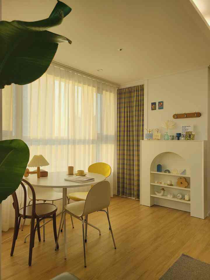 白と黄色のトーンのダイニング、丸いダイニングテーブルと様々なデザインのチェアが配置された雰囲気のある自然な空間