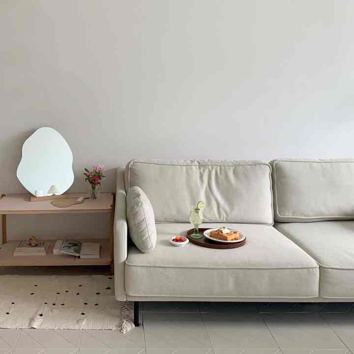 ベージュトーンのリビング、ベージュのファブリックソファと木製トレイが配置されたシンプルで自然な雰囲気のあるインテリア