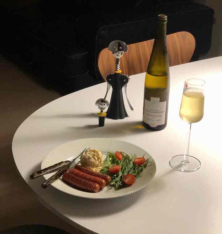 White table in cozy kitchen space featuring wine glass, wine bottle, corkscrew, and simple snacks