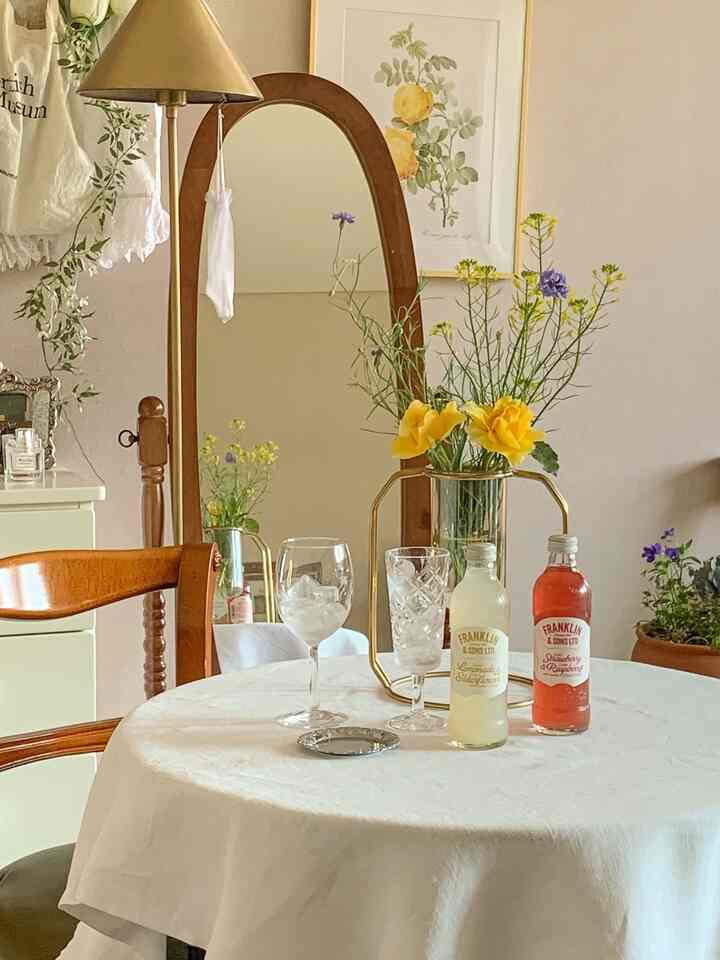 白と木目調のダイニングルーム、木製椅子とゴールドの花瓶が配置された温かみのある雰囲気のあるインテリア