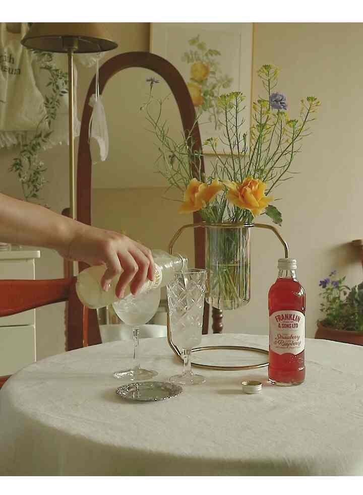 Cozy home cafe scene with gold frame vase and glassware on a white tablecloth