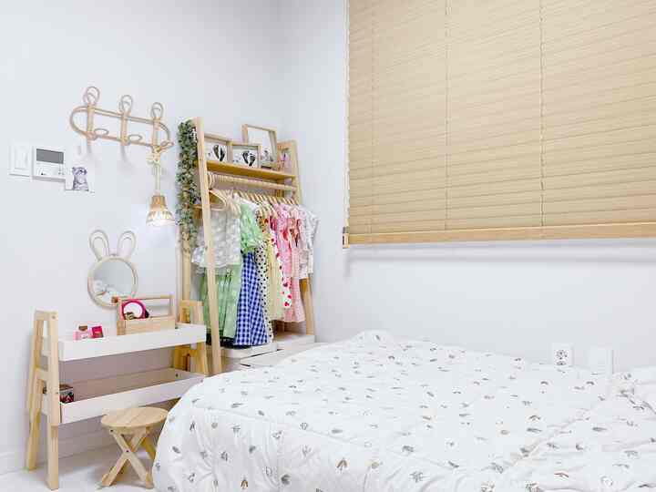 A white and wood-tone kids' room featuring a hanging rack and bed arranged neatly in a cozy bedroom space