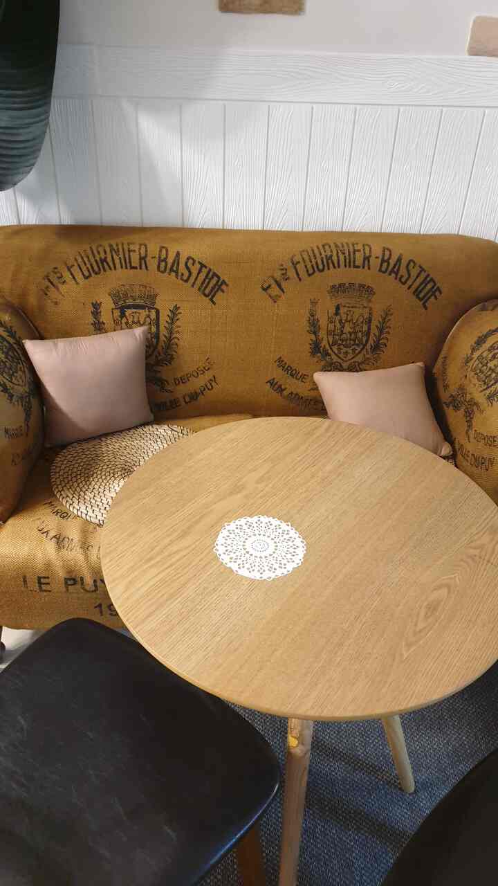 ブラウンと木目調のヴィンテージリビング、2人掛けソファと丸い木製テーブル、黒のレザー椅子が落ち着いた雰囲気を演出