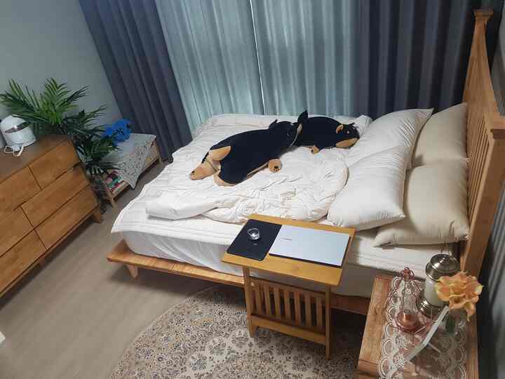 Cozy bedroom with natural wood tones and ivory bedding, featuring dresser and curtains for a warm atmosphere