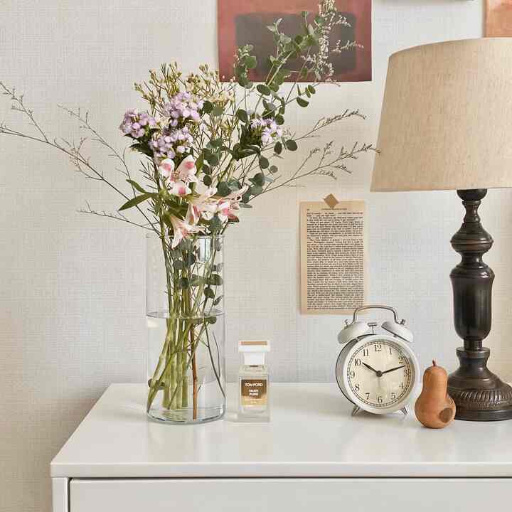 白と茶色のトーンのテーブルに花瓶、ヴィンテージの時計、テーブルランプが配置された自然な雰囲気のインテリア