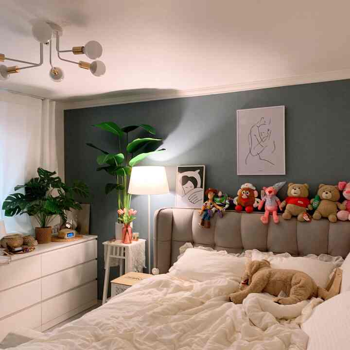 White and green toned bedroom featuring bed, floor lamp, framed art, and plants creating a cozy space