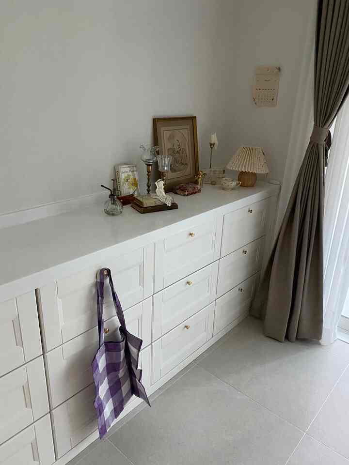 アイボリー調の寝室のビルトインチェストとベージュの遮光カーテンが配された雰囲気のあるインテリア