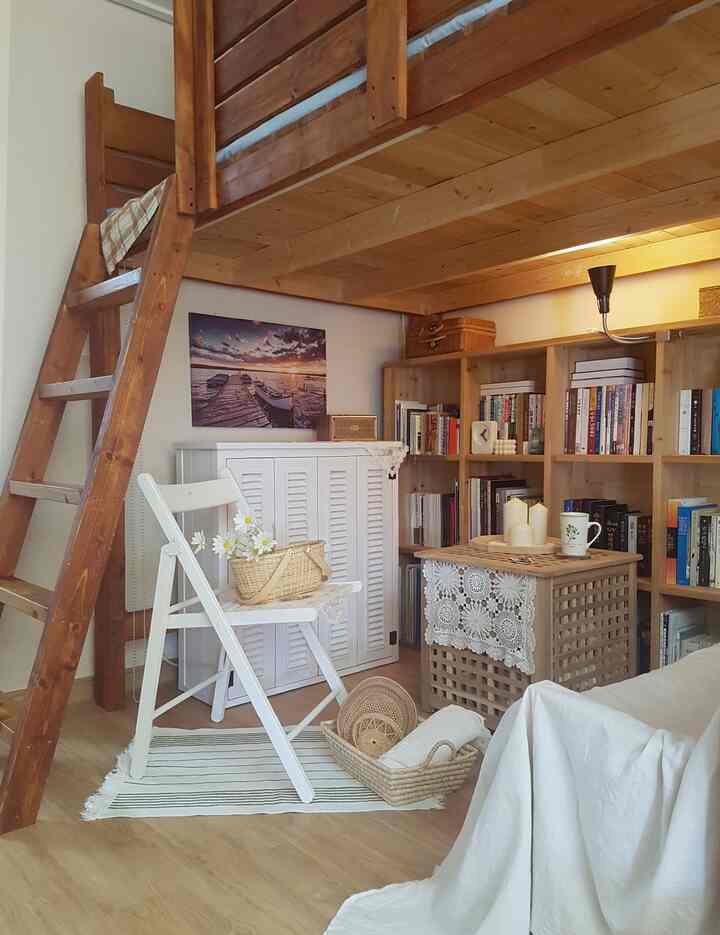 A natural living room featuring white and wood tones, with rattan accessories and a bookshelf creating a cozy atmosphere