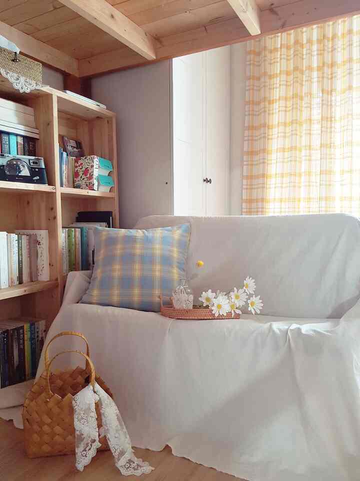Natural style living room with wood tones and yellow plaid curtains, featuring white sofa and bookshelf creating a cozy atmosphere