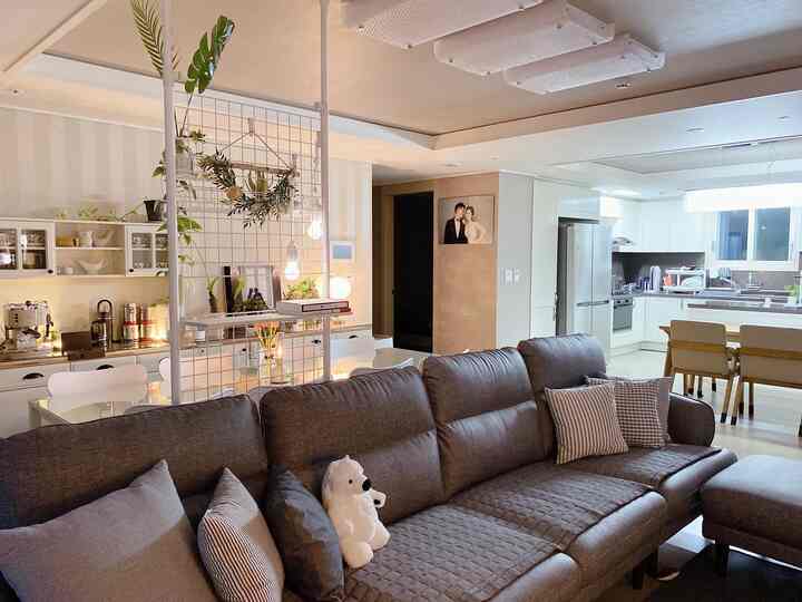 Natural-toned living and kitchen space featuring large brown sofa and dining table with cozy atmosphere