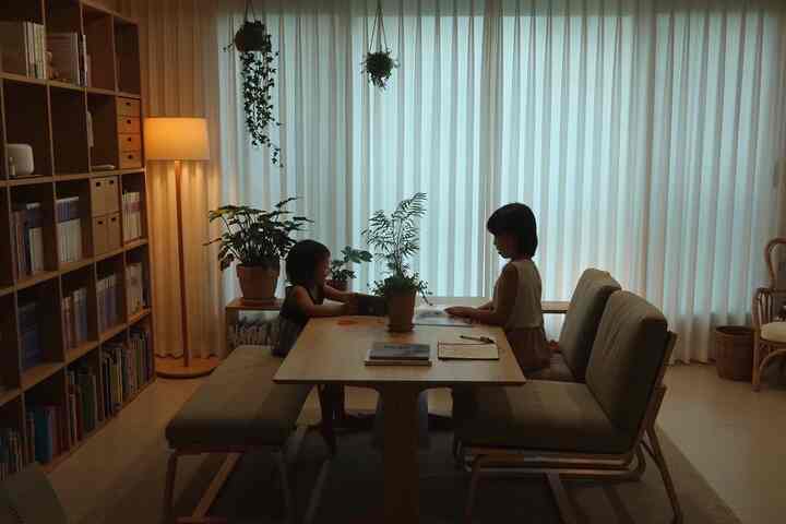 ナチュラルな木目調と白いカーテンが印象的なリビング、ローテーブルと子供用の椅子が配置された雰囲気のあるインテリア