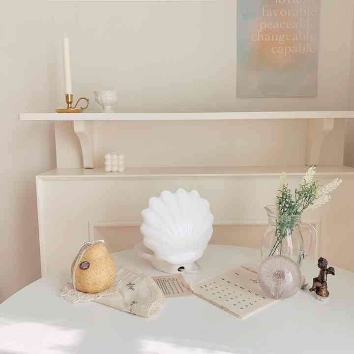 White and beige toned living space featuring a round table with candles, vase, and decorative elements creating a natural and cozy atmosphere
