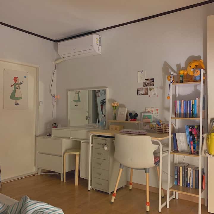 ホワイトと木目調の化粧台とデスクが配置され、かわいい小物やライアンのぬいぐるみがある、温かみのある雰囲気のインテリア