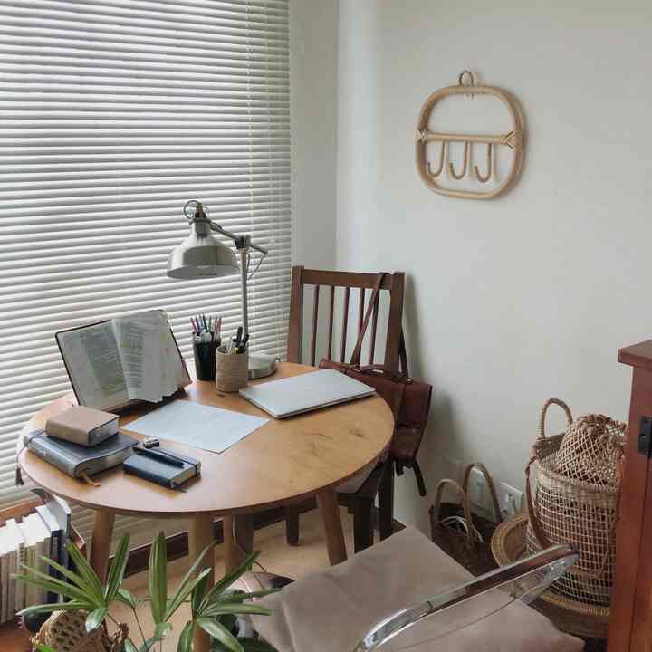 Ivory walls and white blinds in a Scandinavian-style small study featuring a round wooden desk and chair creating a cozy atmosphere