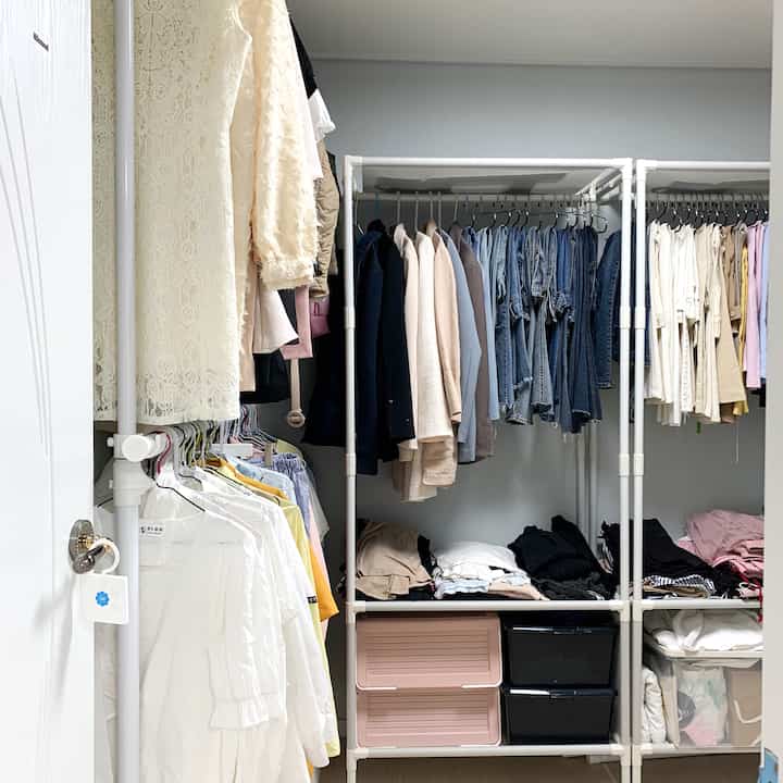 白を基調としたウォークインクローゼット、洋服ラックと折りたたみ収納ボックスが配置された空間